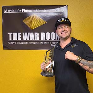 Martindale Pinnacle Construction owner holding reward in front of war room sign